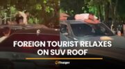 Иностранец, заметивший себя, расслабляясь на крыше внедорожника во время движения в Пхукете